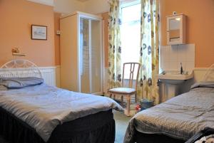 a bedroom with two beds and a sink and a window at Brookfield Guesthouse in Cleethorpes