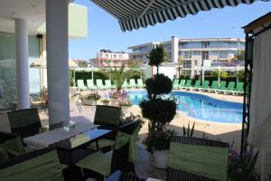 eine Terrasse mit Tisch und Stühlen und ein Swimmingpool in der Unterkunft Семеен Хотел Идън in Sweti Wlas