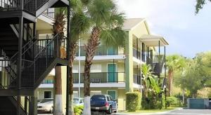 a car parked in front of a building with palm trees at Sunstyle Suites in Orlando