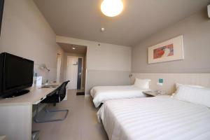 Cette chambre comprend deux lits, un bureau et une télévision. dans l'établissement Jinjiang Inn Tonghua Shengli Road Branch, à Tonghua