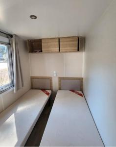 Una pequeña habitación con dos camas y una ventana. en MOBILE-HOME Bonne Anse plage, en Les Mathes