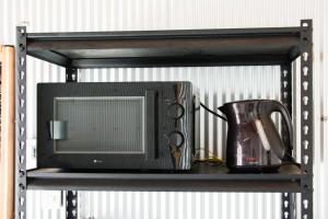 a black shelf with a microwave and a pitcher on it at Rockstar Villa 江井浜STYLE in Awaji +17 photos