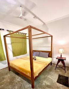 a bedroom with a canopy bed with a yellow mattress at Coastal Cloud Backpackers in Unawatuna