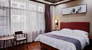 ein Schlafzimmer mit einem großen Bett und einem Stuhl in der Unterkunft Jun Hotel Guangxi Wuzhou Changzhou District Fengye Garden in Wuzhou