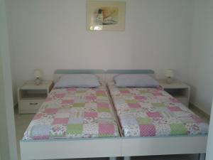 a bed with a quilt on it with two tables at Apartments MiaMaja in Novalja
