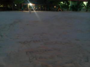 a person is standing in the sand at night at Magic's Place Beach Resort in Saavedra