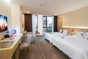 una camera d'albergo con 2 letti e una scrivania di Stella Maris Nha Trang Hotel a Nha Trang