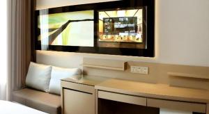 une chambre avec un bureau et un miroir au mur dans l'établissement Lavande Hotel Wuhan Huanghelou Branch, à Wuhan