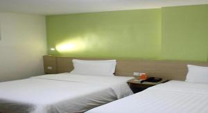 two beds in a room with a green wall at 7 Days Inn Bijie Jinsha Hebin Road in Jinsha