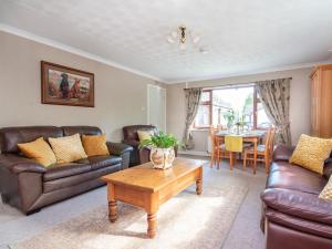 a living room with leather couches and a coffee table at Black Rock Cottage in Culbokie