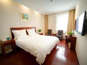 une chambre avec un grand lit blanc et une télévision dans l'établissement GreeTree Inn Suzhou Industrial Jinji Lake Xinhujie Gaojiaoqu, à Suzhou