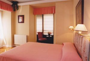 a bedroom with a bed and a chair and a window at Torre Ercilla Ostatua in Bermeo