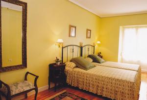 a bedroom with a bed and a mirror and a chair at Torre Ercilla Ostatua in Bermeo