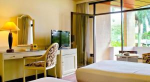 a bedroom with a bed and a desk with a television at Purnama Hotel in Malang