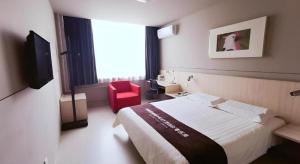a hotel room with a bed and a red chair at Jinjiang Inn Handan Zhonghua Nan Street Xueyuan Bei Road in Handan