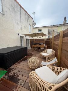 a patio with wicker chairs and a table and a grill at Cocon avec jacuzzi in Périgny