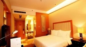 une chambre d'hôtel avec un lit, un bureau et une lampe dans l'établissement Ramada Plaza by Wyndham Yangzhou Casa, à Yangzhou