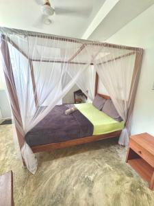 a bedroom with a bed with a mosquito net at Coastal Cloud Backpackers in Unawatuna