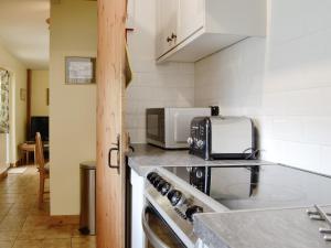 a kitchen with a stove and a microwave at Beck Cottage in Ennerdale Bridge