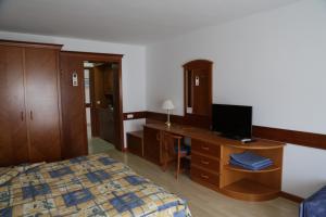 1 dormitorio con 1 cama y escritorio con TV en Vesta Apartments, en Hévíz
