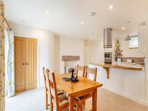 een keuken en eetkamer met een houten tafel en stoelen bij Rose Cottage - Uk39245 in Inverness