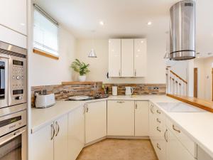 een keuken met witte kasten en witte apparaten bij Rose Cottage - Uk39245 in Inverness +17 foto's