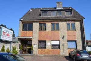 an old brick building with a car parked in front of it at Top Hotel Garni, Modus Hotelbetriebe GmbH in Dormagen