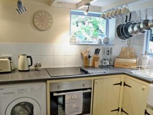 a kitchen with a washing machine and a clock on the wall at Fairmaiden in Polruan