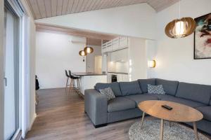 Una sala de estar con un sofá azul y una mesa. en Charming Cottage In Fjellerup With Indoor Spa, en Glesborg