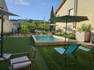 a backyard with a pool and chairs and an umbrella at Partie de villa in Velleron +19 photos