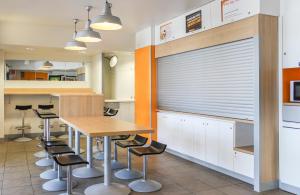 a kitchen with a table and some stools at Lemon Hôtel Coudes in Coudes