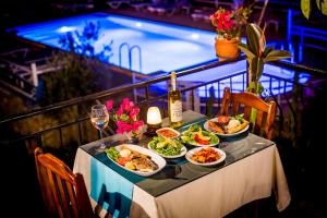 a table with plates of food and a swimming pool at Flower Hotel Patara in Patara