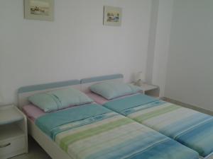a bed in a room with two pillows on it at Apartments MiaMaja in Novalja