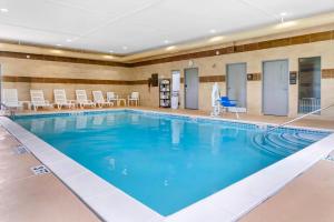 a large swimming pool in a hotel room with chairs at Comfort Suites Auburn Hills-Detroit in Auburn Hills