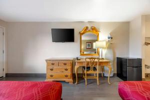 a hotel room with a desk and a mirror at Rodeway Inn Albany in Albany