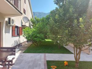 a courtyard with a tree and two dogs in the grass at Apartman Matea in (( Glavati )) +6 photos