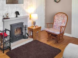 ein Wohnzimmer mit Kamin und Sessel in der Unterkunft Honeysuckle Cottage in Luncarty