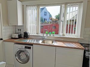 eine Küche mit Spüle und Waschmaschine in der Unterkunft Honeysuckle Cottage in Luncarty