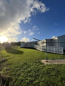 ein Gebäude mit einem weißen Zaun neben einem Feld in der Unterkunft Te Tihi Noho Shared Accommodation 