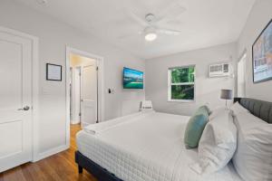 a white bedroom with a large bed and a ceiling fan at Condo by the Beach King Bed Lush Patio w BBQ Breakers Key Six H0MES in Fort Lauderdale