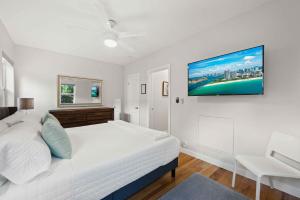 a white bedroom with a bed and a tv on the wall at Condo by the Beach King Bed Lush Patio w BBQ Breakers Key Six H0MES in Fort Lauderdale