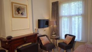 ein Wohnzimmer mit Stühlen und einem Fernseher und einem Fenster in der Unterkunft City Lodge Stay A while in Zwolle