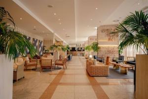 a lobby with chairs and tables and plants at TRYP by Wyndham Lisboa Caparica Mar in Costa da Caparica +37 photos