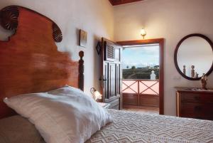 a bedroom with a bed and a mirror and a window at Ecofinca La Buganvilla - Adults Only in San Bartolomé