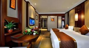 a bedroom with two beds and a table and a television at Yitel Collection Chengdu Kuanzhai Alley Chutian Junlin in Chengdu