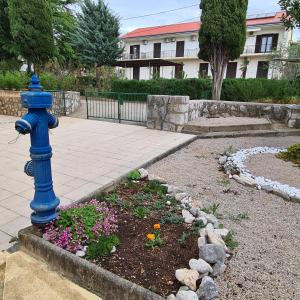 a blue fire hydrant in a garden with flowers at Letovišče primarija Kurta Kanclerja Punat in Punat