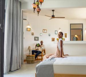 a young girl sitting on a bed in a room at Pili Pili Tropical Island in Jambiani