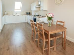 a kitchen with a wooden table with chairs and a vase of flowers at Sea Is All Around in Mundesley