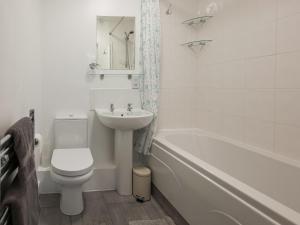 a bathroom with a toilet and a sink and a tub at Sea Is All Around in Mundesley +3 photos