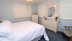una camera con letto bianco, cassettiera e specchio di Cliffside Cottage a North Cape May